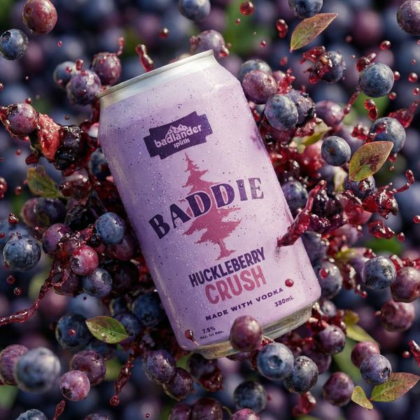 Can of Badlander Huckleberry Crush in a pile of plump Montana Huckleberries.