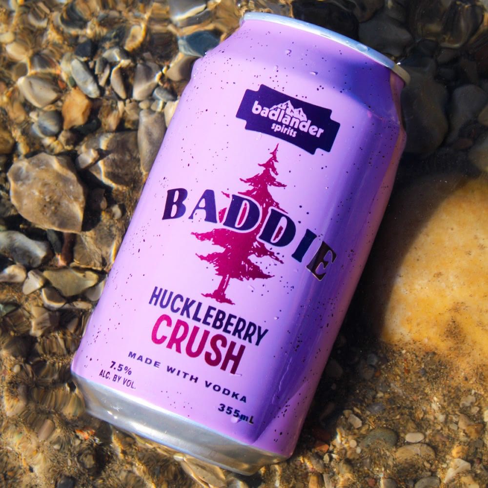A can of Badlander Huckleberry Crush resting in a pool of spring water.