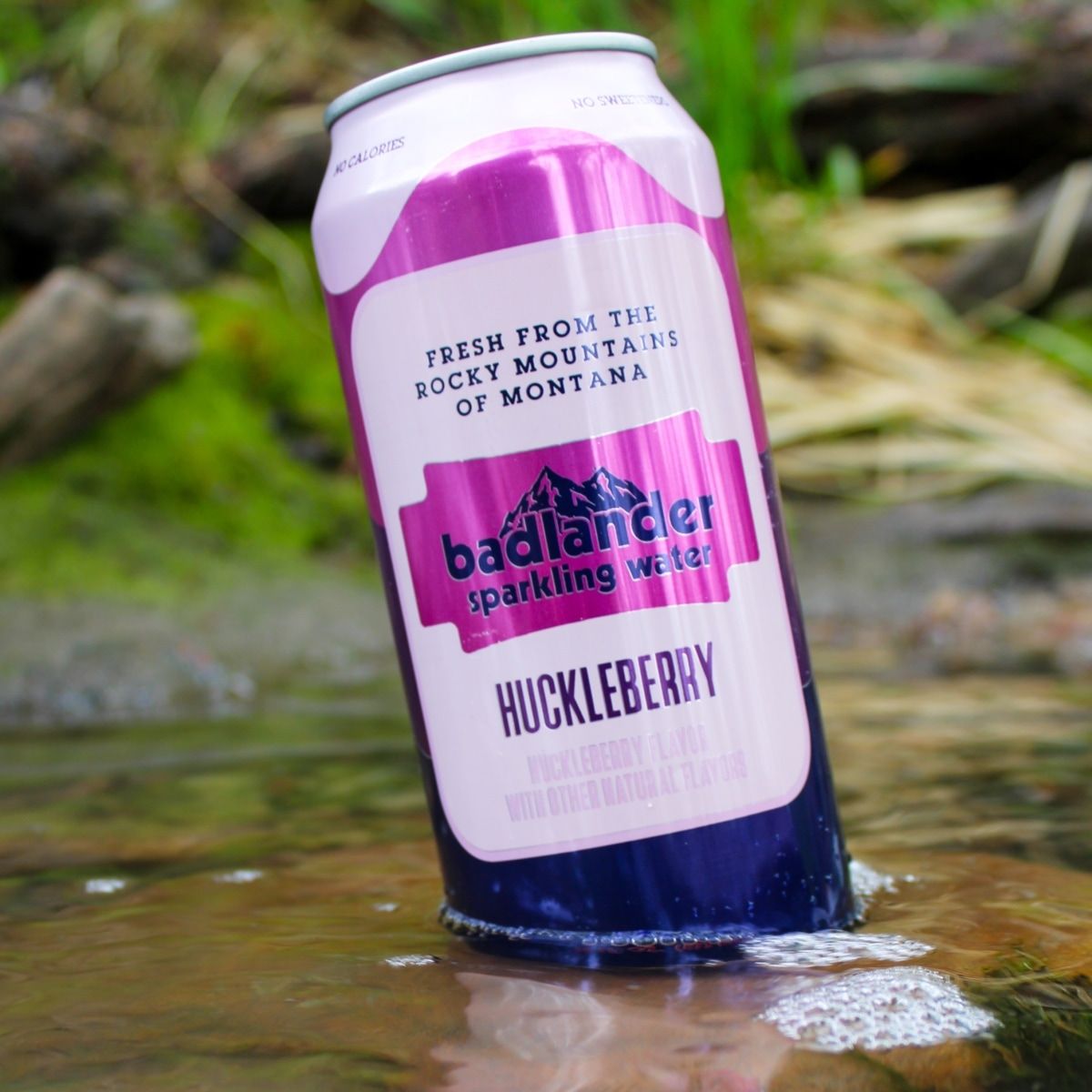 A can of Badlander Huckleberry Seltzer water resting in mountain spring.